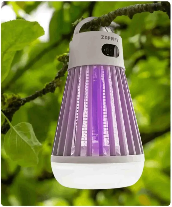 Portable bug zapper hanging from a branch among green leaves